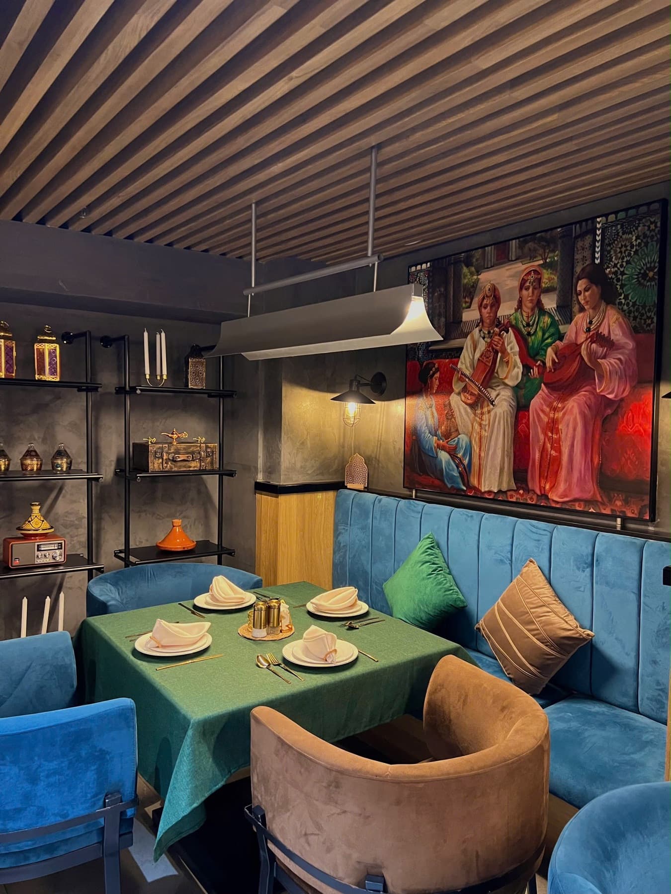 The Naadi dining room: emerald velvet, Moroccan paintings, warm light